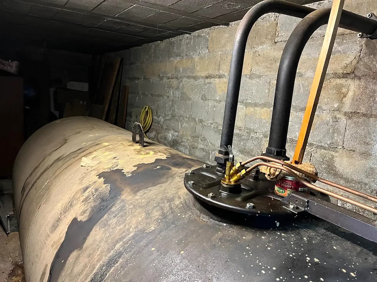 Cuve à fioul en cave, trou d'homme et tuyaux d'aspiration vers la chaudière