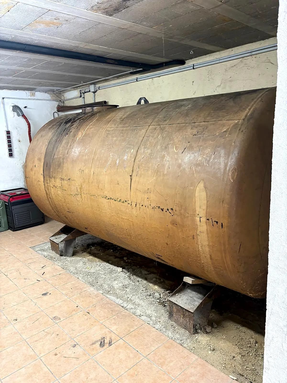 Grande cuve à fioul cylindrique sur berceaux dans un garage carrelé