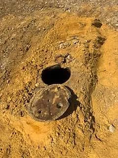 Cuve à fioul enterrée mise au jour par la pelleteuse, trou d'homme ouvert
