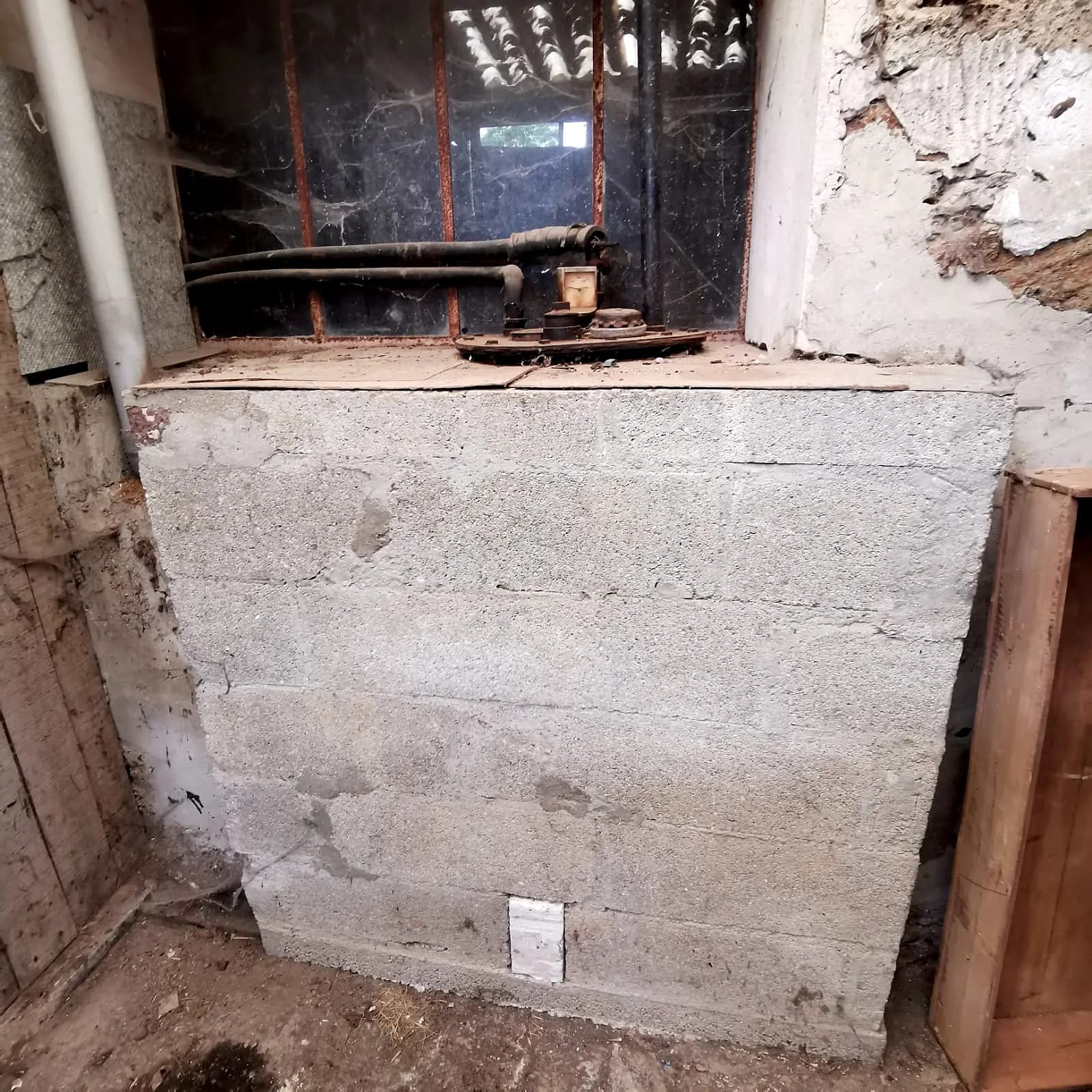 Cuve à fioul murée derrière un muret de parpaings dans une cave
