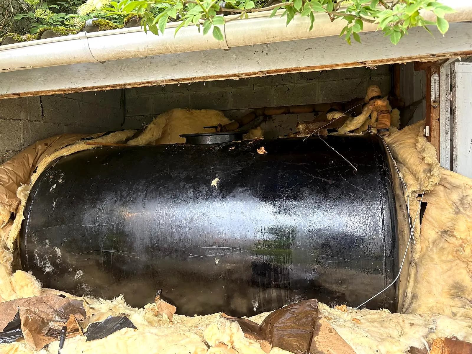 Cuve à fioul noire logée sous une maison, dans un vide sanitaire